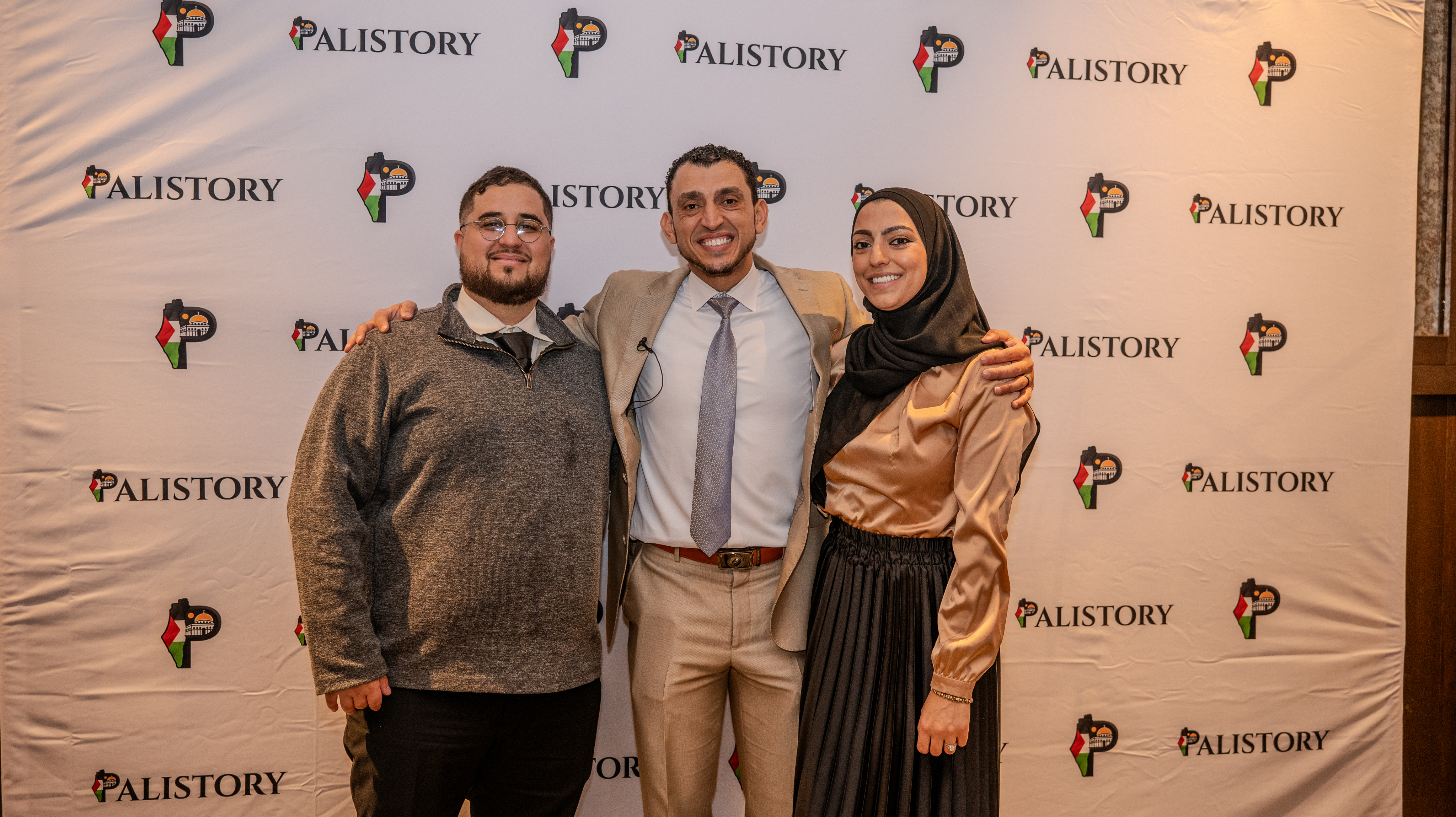 Ibrahim J. Awad with two colleagues at a Palistory event, in front of a Palistory step-and-repeat banner