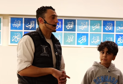 Ibrahim J. Awad, wearing a headset microphone, speaking with a young boy during an anti-bullying workshop