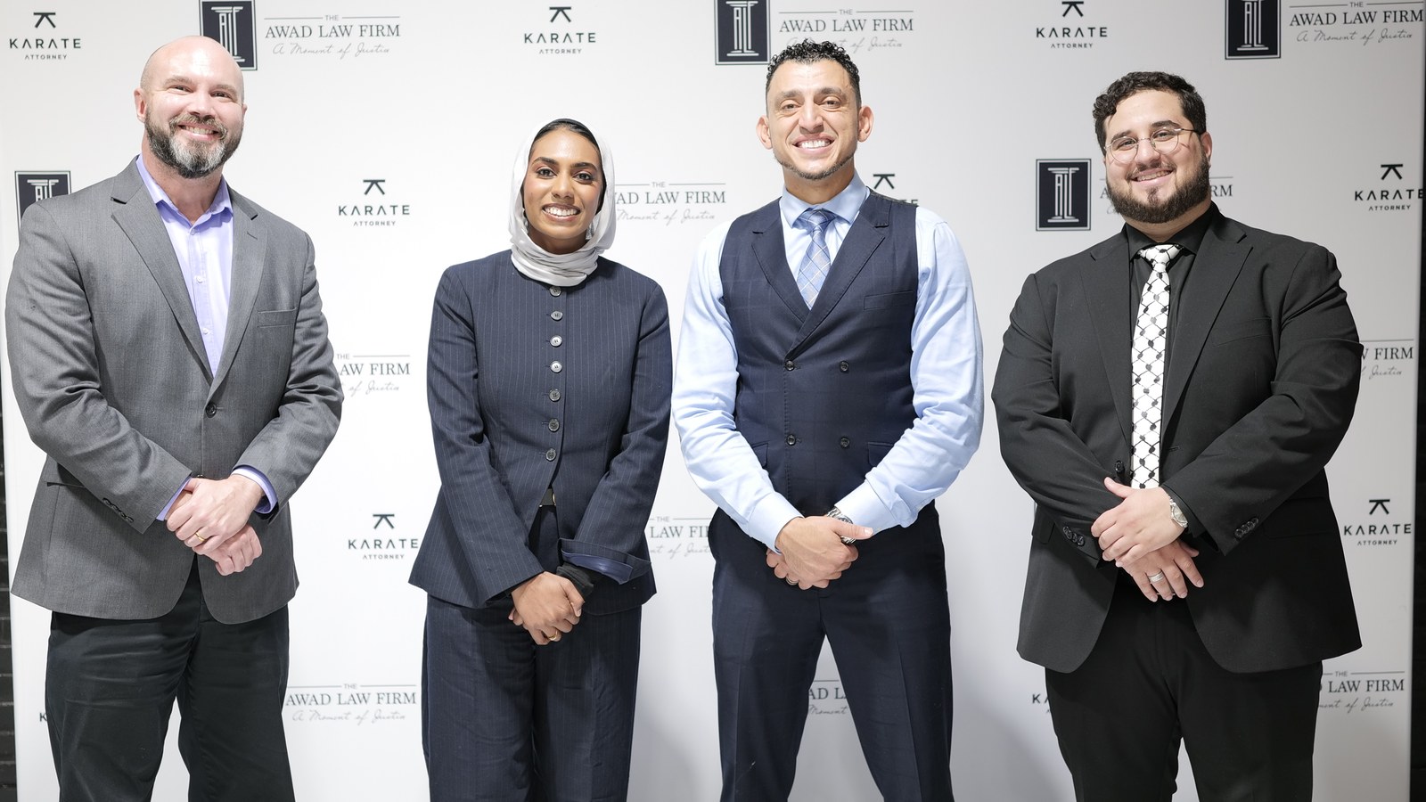 Ibrahim J. Awad with three colleagues in front of an Awad Law Firm and Karate Attorney backdrop