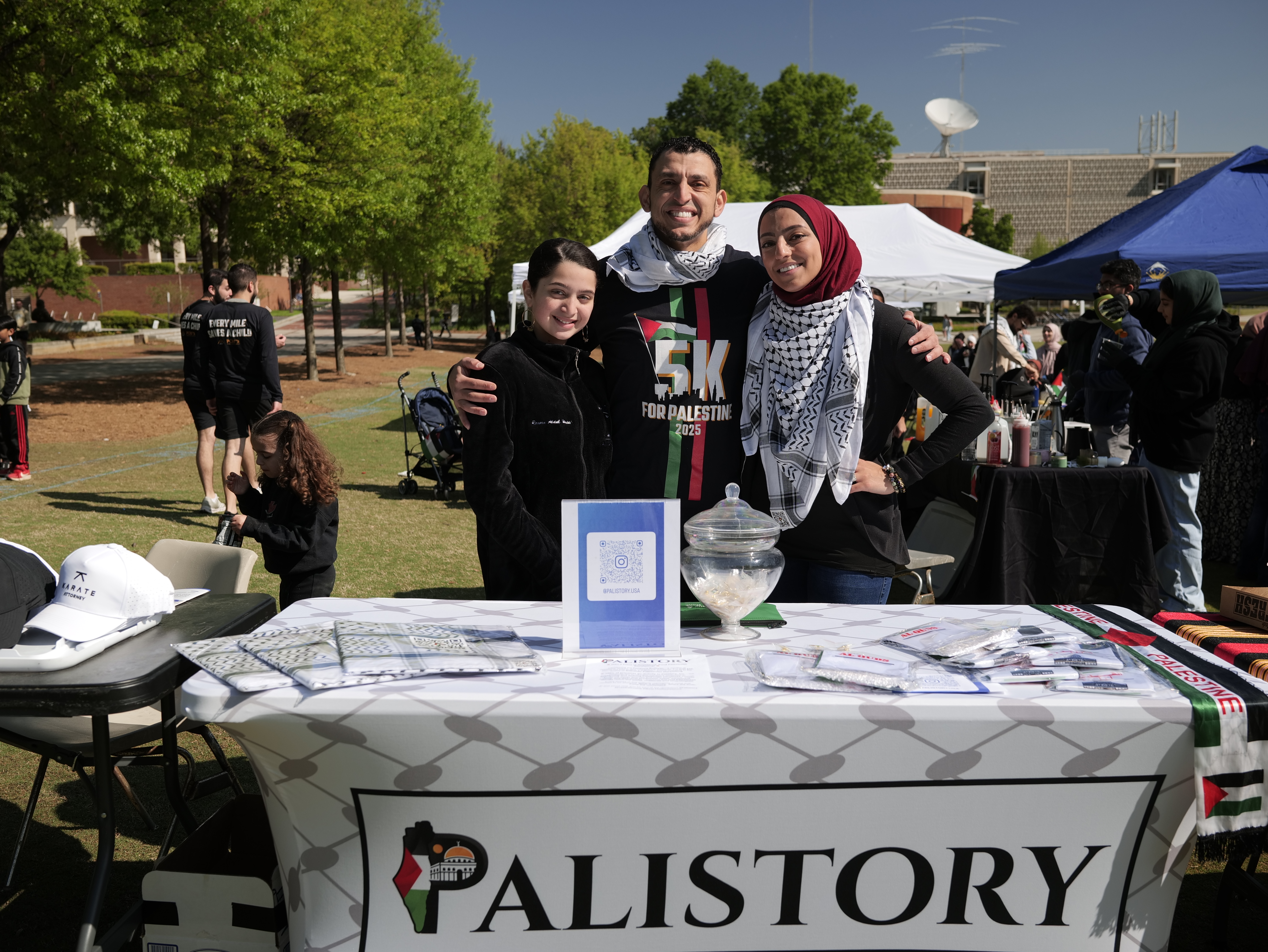 Ibrahim J. Awad and two others behind the Palistory stall at a 5K for Palestine event