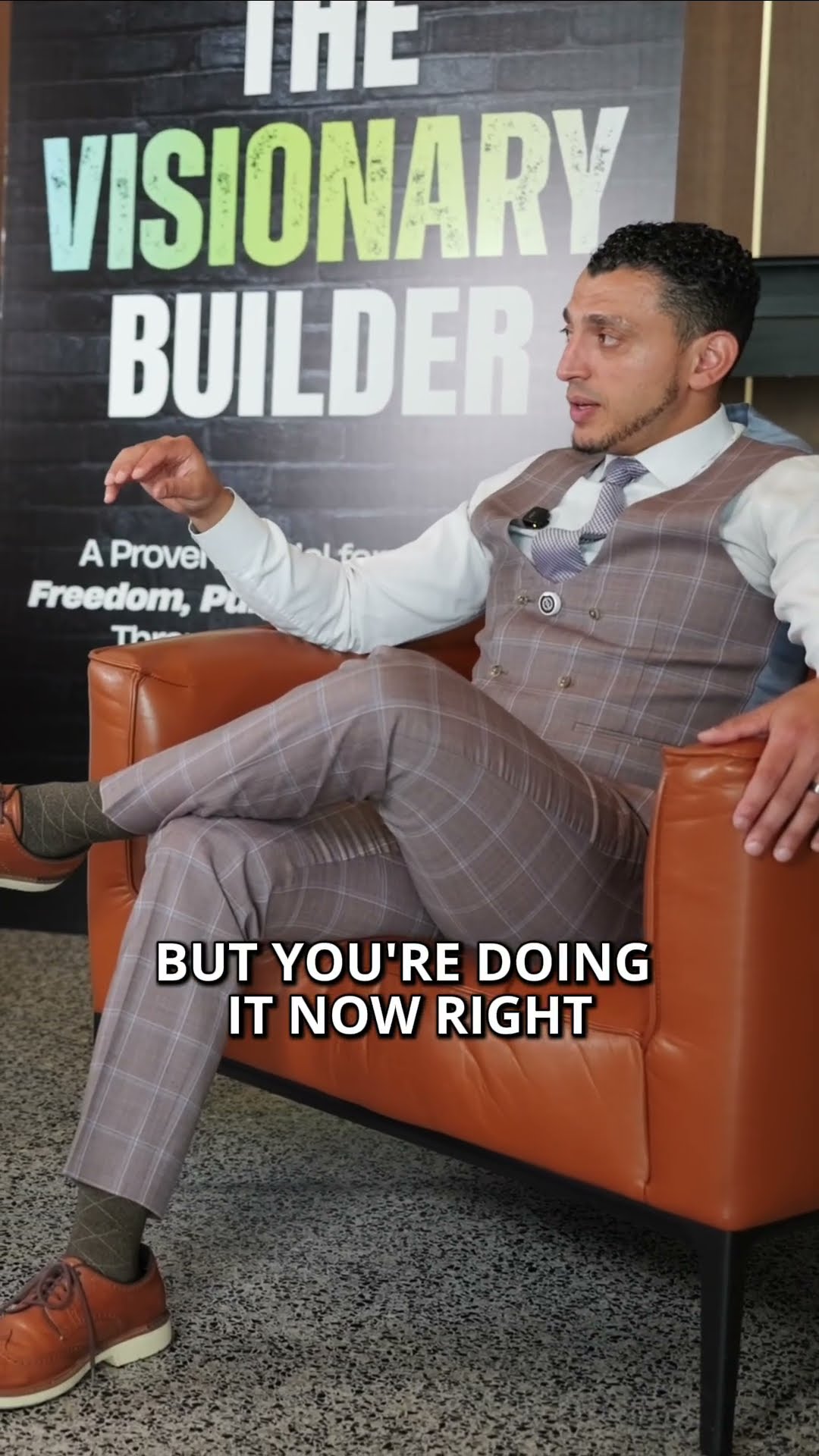 Ibrahim J. Awad in a checked waistcoat, mid-interview on The Visionary Builder podcast