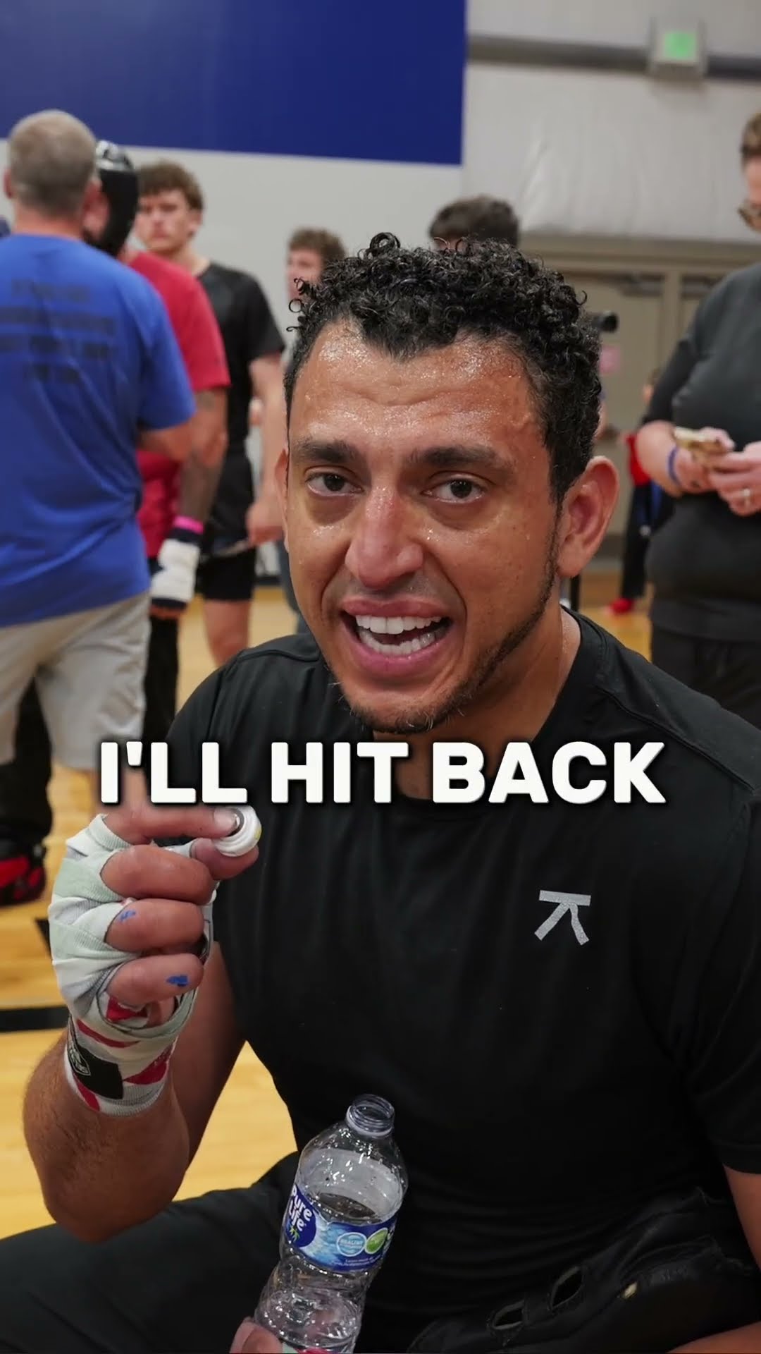 Ibrahim J. Awad courtside in training gear with taped hands, captioned "I'll hit back"
