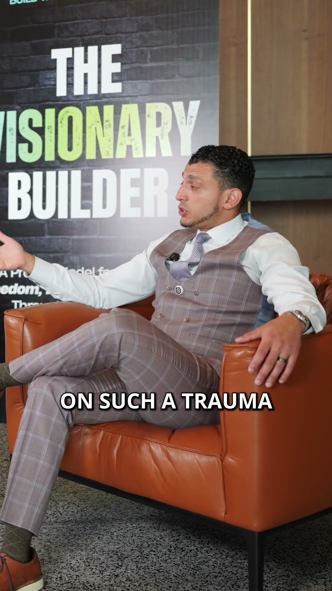 Ibrahim J. Awad mid-sentence in the podcast chair, captioned "On such a trauma"