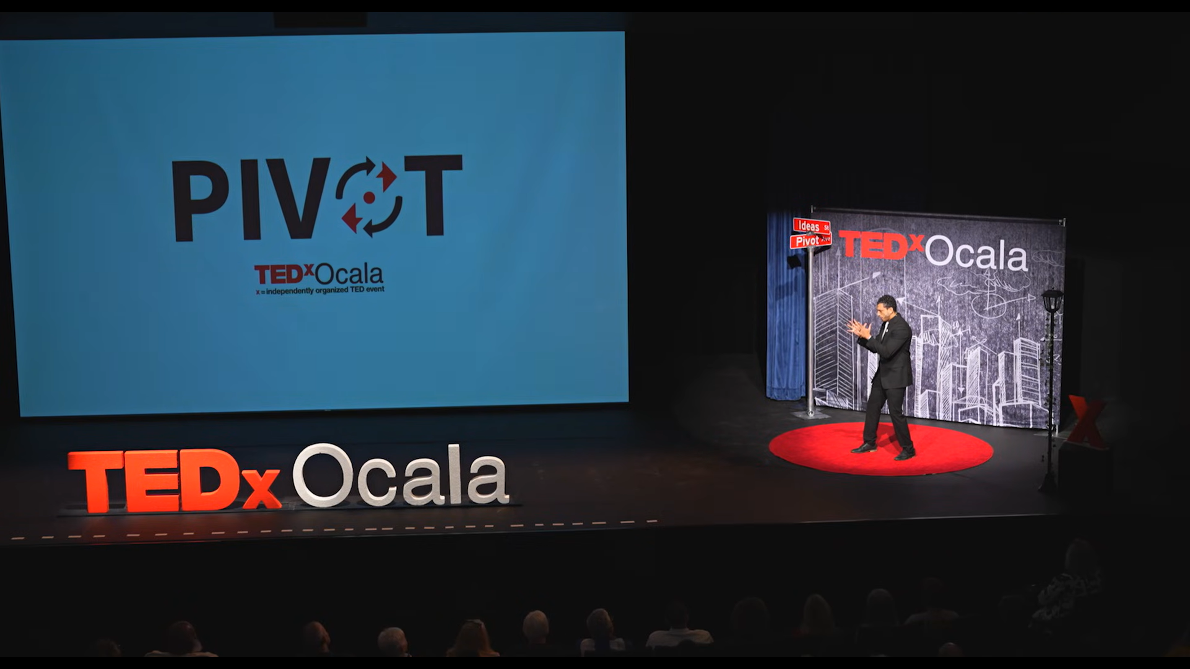 Ibrahim J. Awad on stage at TEDxOcala, addressing a seated audience